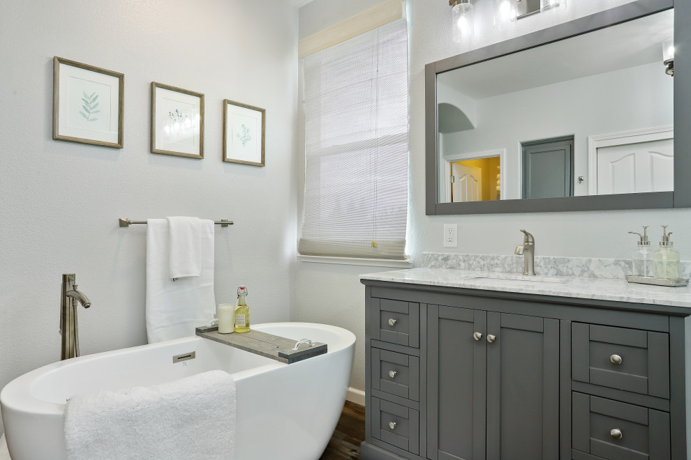 Foto de cuarto de baño principal, único y de pie, actual, con puertas de armario grises, bañera exenta, ducha esquinera, paredes grises, suelo laminado, lavabo bajoencimera, encimera de mármol, suelo marrón, ducha con puerta con bisagras y encimeras grises