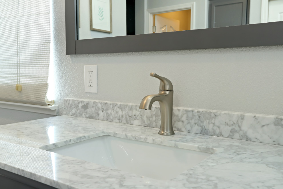 Modern inredning av ett grå grått en-suite badrum, med grå skåp, ett fristående badkar, en hörndusch, grå väggar, laminatgolv, ett undermonterad handfat, marmorbänkskiva, brunt golv och dusch med gångjärnsdörr