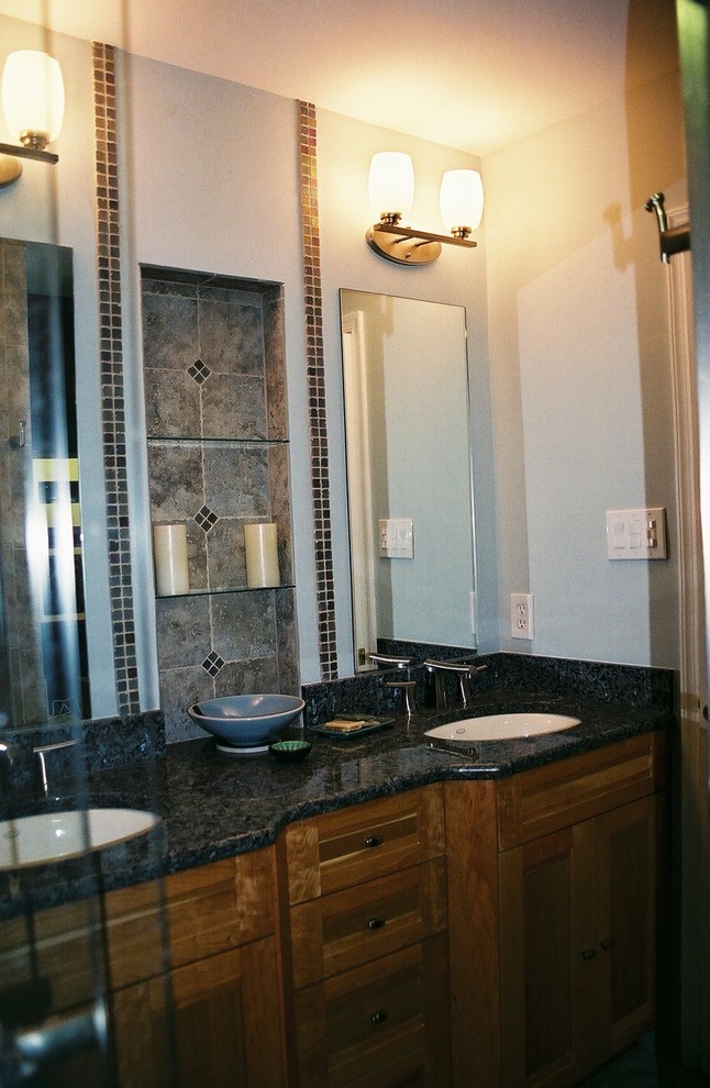 Foto di una stanza da bagno etnica di medie dimensioni con lavabo da incasso, consolle stile comò, ante in legno scuro, top in granito, doccia ad angolo, piastrelle nere, piastrelle in pietra e pareti bianche