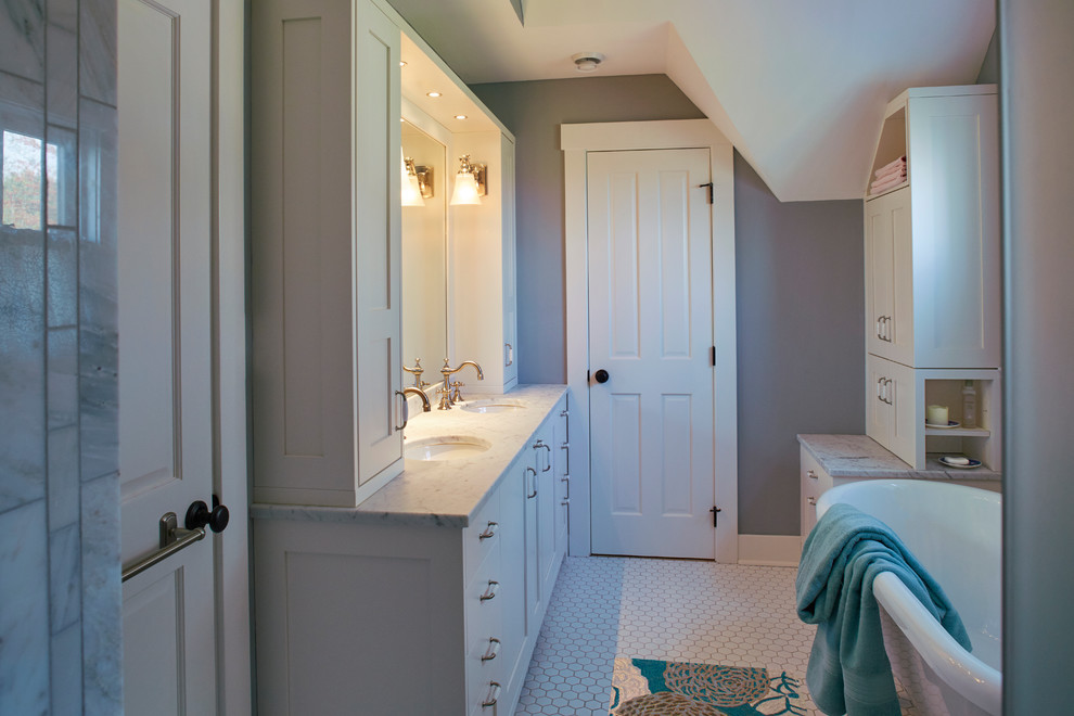 Photo of a country bathroom in Minneapolis with recessed-panel cabinets, white cabinets, a claw-foot bath, grey tiles, marble tiles, blue walls, mosaic tile flooring and white floors.