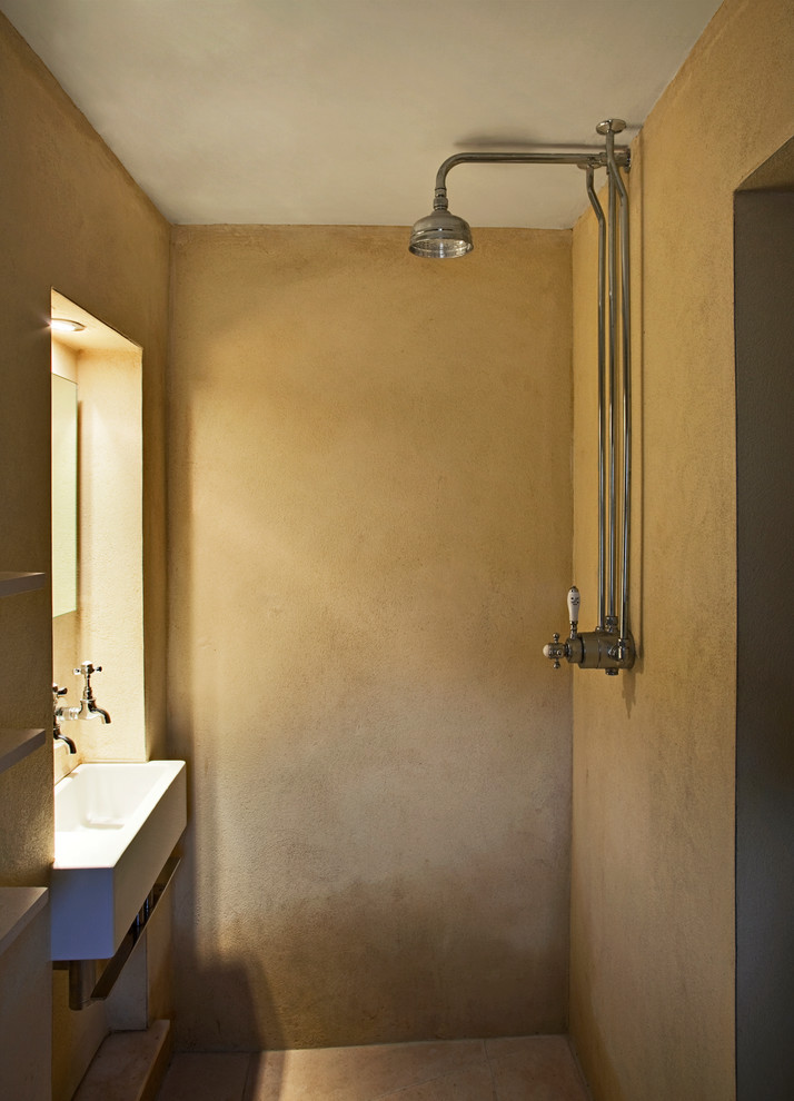 Kleines Modernes Badezimmer mit integriertem Waschbecken, Badewanne in Nische, offener Dusche, Wandtoilette mit Spülkasten, gelber Wandfarbe, Kalkstein, offener Dusche und Kalkfliesen in Devon