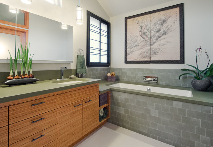 Aménagement d'une salle de bain asiatique en bois brun avec un lavabo encastré, un placard à porte plane, une baignoire encastrée, un carrelage vert et des carreaux de porcelaine.