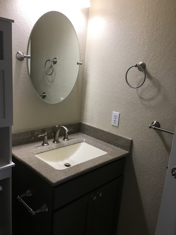 Example of a small transitional 3/4 beige tile ceramic tile and beige floor bathroom design in Denver with shaker cabinets, dark wood cabinets, a two-piece toilet, beige walls, an integrated sink, solid surface countertops and gray countertops
