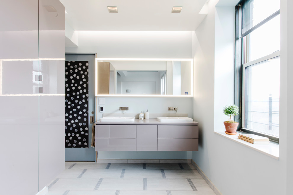 Photo of a contemporary bathroom in New York with flat-panel cabinets, grey cabinets, white walls, a vessel sink, beige floors and grey worktops.