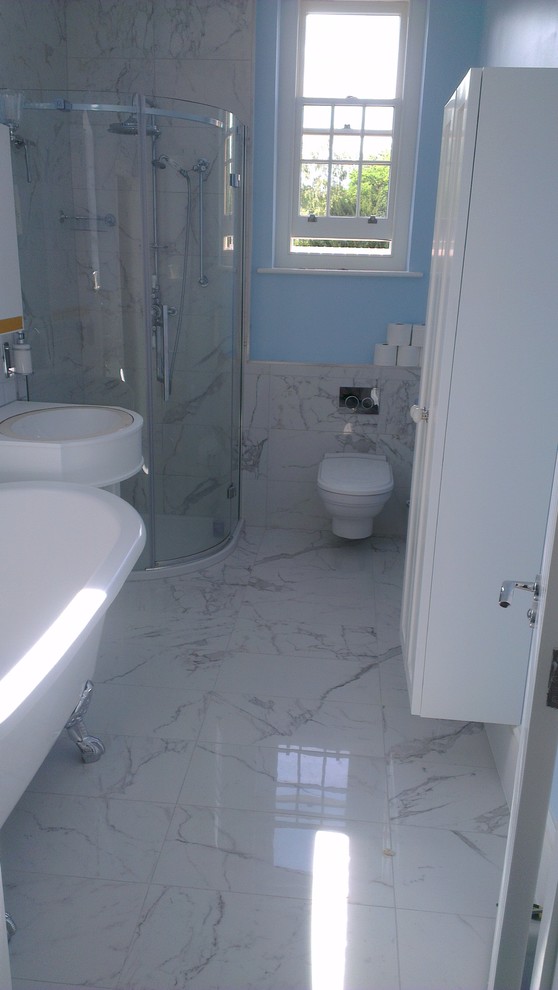 На фото: ванная комната среднего размера в викторианском стиле с ванной на ножках, угловым душем, инсталляцией, белой плиткой, керамической плиткой, синими стенами, полом из керамической плитки и консольной раковиной с