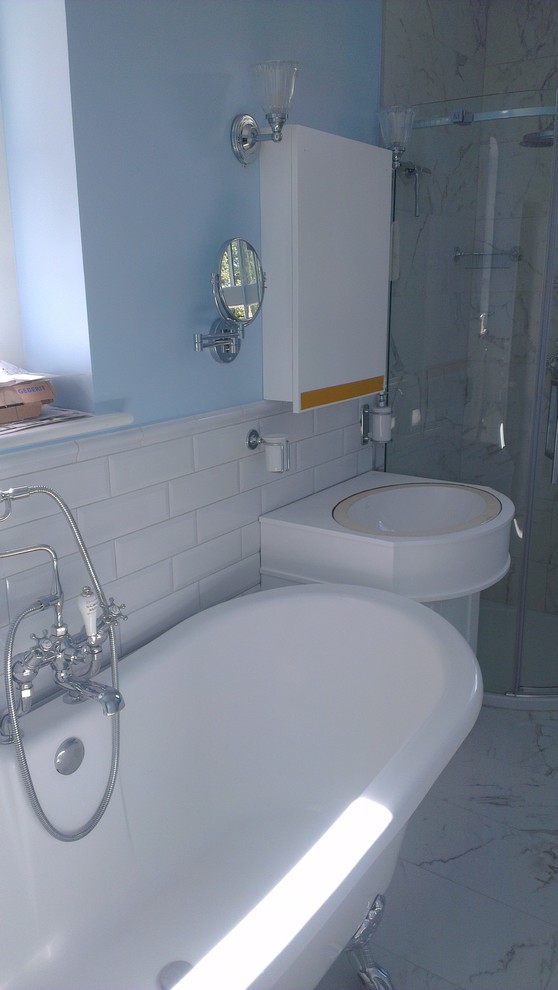 Cette photo montre une salle de bain victorienne de taille moyenne avec une baignoire sur pieds, une douche d'angle, WC suspendus, un carrelage blanc, des carreaux de céramique, un mur bleu, un sol en carrelage de céramique et un plan vasque.