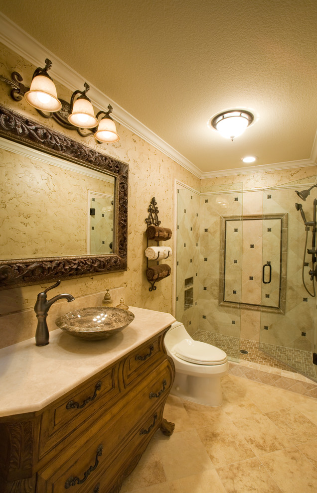 Example of a mid-sized classic 3/4 beige tile and travertine tile travertine floor and brown floor alcove shower design in Dallas with furniture-like cabinets, dark wood cabinets, a one-piece toilet, beige walls, a vessel sink, quartzite countertops and a hinged shower door