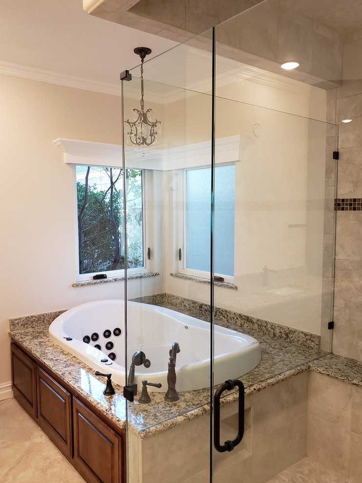 Inspiration for a large timeless master beige tile and stone slab porcelain tile and beige floor bathroom remodel in Dallas with a vessel sink, granite countertops, a hinged shower door, raised-panel cabinets, dark wood cabinets, beige walls and multicolored countertops