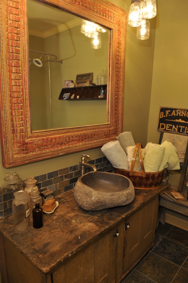 Exempel på ett klassiskt badrum, med ett fristående handfat, möbel-liknande, skåp i slitet trä, träbänkskiva, ett badkar med tassar, en dusch/badkar-kombination, en toalettstol med separat cisternkåpa, flerfärgad kakel, keramikplattor, gröna väggar och klinkergolv i keramik