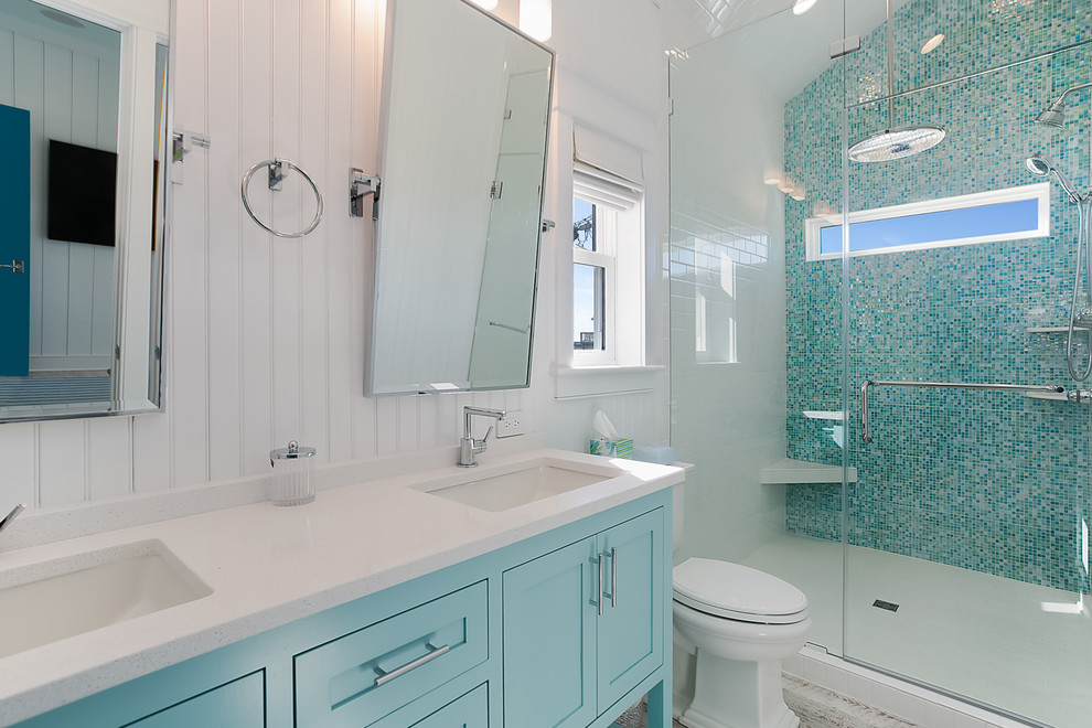 Foto di una stanza da bagno padronale costiera di medie dimensioni con ante in stile shaker, ante blu, WC a due pezzi, piastrelle di vetro, pavimento in vinile, lavabo sottopiano e top in pietra calcarea