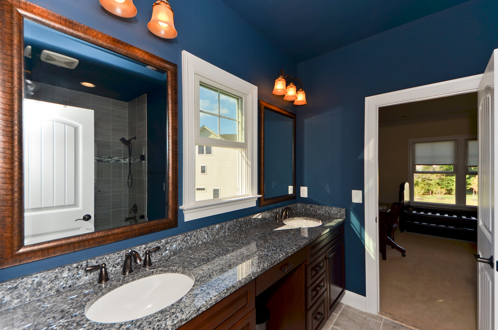 Ejemplo de cuarto de baño actual grande con armarios con paneles con relieve, puertas de armario de madera en tonos medios, paredes azules, suelo de pizarra, lavabo bajoencimera y encimera de granito