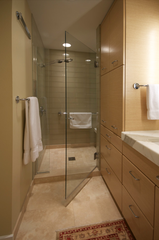 Photo of a small contemporary ensuite bathroom in Other with a submerged sink, flat-panel cabinets, light wood cabinets, marble worktops, an alcove shower, a one-piece toilet, grey tiles, glass tiles, beige walls and travertine flooring.