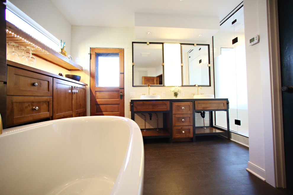 Large industrial ensuite bathroom in Minneapolis with a built-in sink, recessed-panel cabinets, medium wood cabinets, concrete worktops, a freestanding bath, an alcove shower, a one-piece toilet, white tiles, porcelain tiles, white walls and cork flooring.