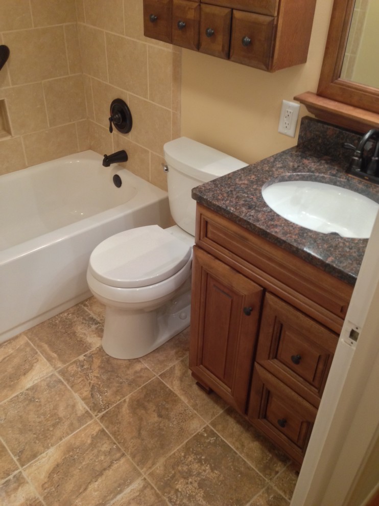 Mid-sized elegant master beige tile and ceramic tile ceramic tile bathroom photo in Cleveland with an undermount sink, raised-panel cabinets, medium tone wood cabinets, granite countertops, a two-piece toilet and beige walls