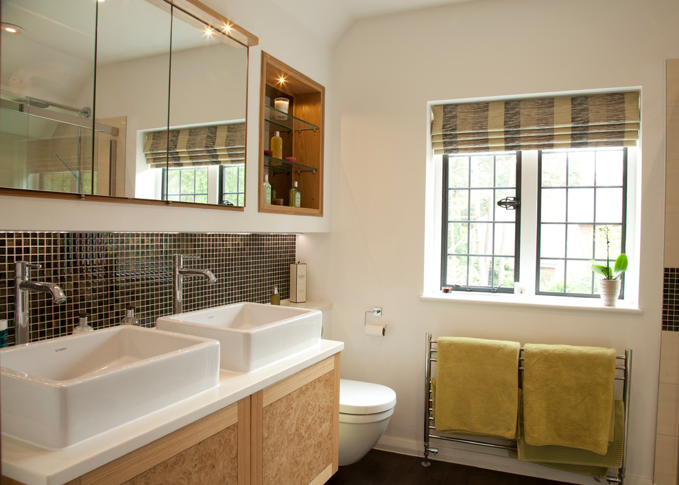 Diseño de cuarto de baño clásico con lavabo sobreencimera, baldosas y/o azulejos negros, baldosas y/o azulejos en mosaico, paredes blancas y puertas de armario de madera clara