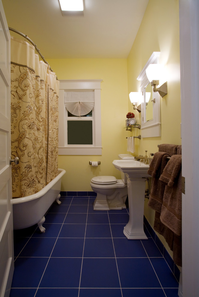 Kleines Uriges Badezimmer mit Sockelwaschbecken, Schrankfronten mit vertiefter Füllung, weißen Schränken, Löwenfuß-Badewanne, Wandtoilette mit Spülkasten, blauen Fliesen, Keramikfliesen, gelber Wandfarbe und Keramikboden in Charleston