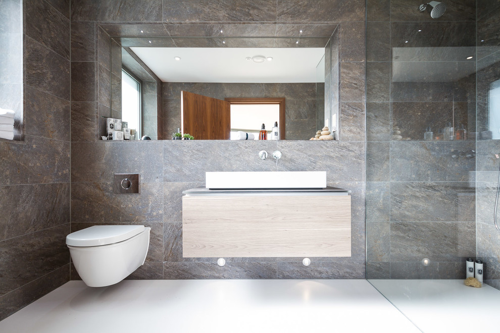 Пример оригинального дизайна: ванная комната в современном стиле с настольной раковиной, плоскими фасадами, светлыми деревянными фасадами, душем без бортиков, инсталляцией и серой плиткой