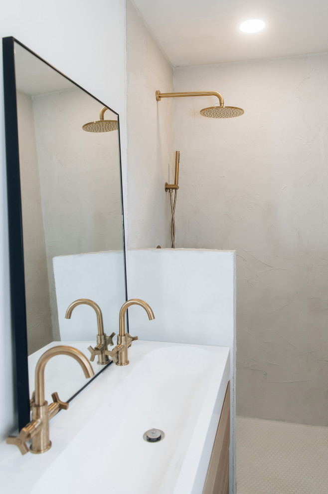Inredning av ett retro litet vit vitt en-suite badrum, med släta luckor, skåp i ljust trä, en dusch i en alkov, vita väggar, cementgolv, bänkskiva i akrylsten och blått golv