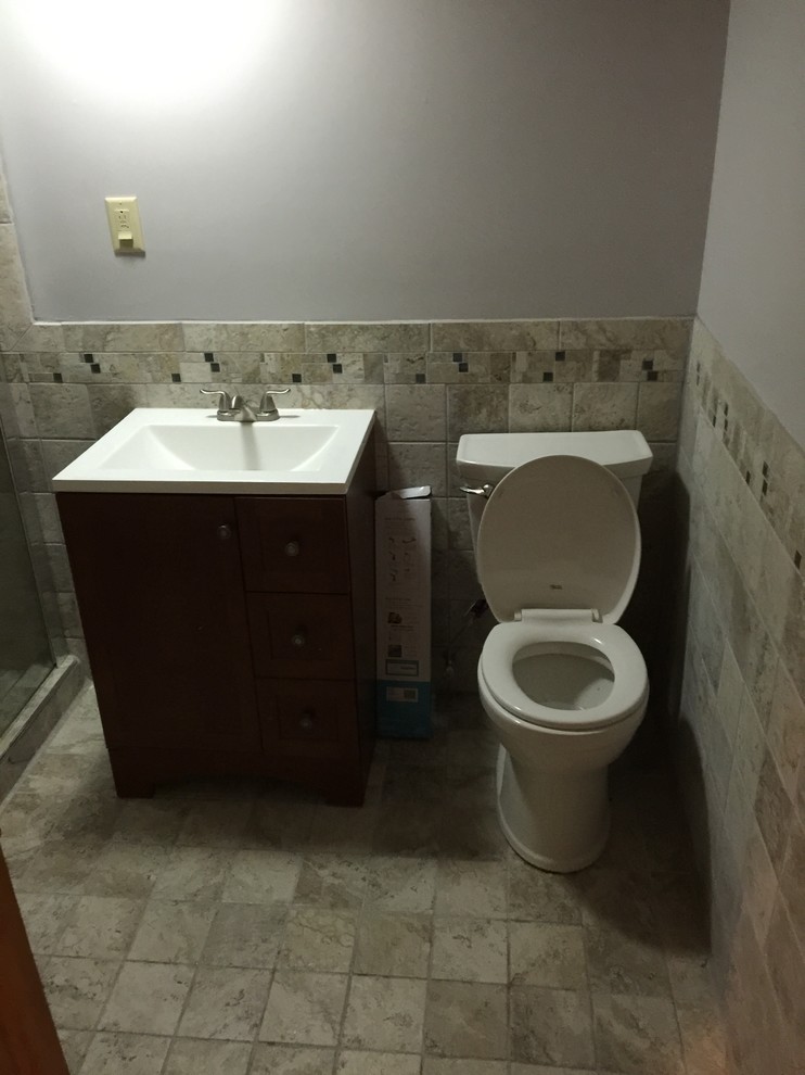 Exempel på ett litet klassiskt badrum med dusch, med skåp i mörkt trä, keramikplattor, grå väggar, klinkergolv i keramik, bänkskiva i akrylsten, skåp i shakerstil, en dusch i en alkov, en toalettstol med separat cisternkåpa, grå kakel, ett integrerad handfat, grått golv och dusch med skjutdörr