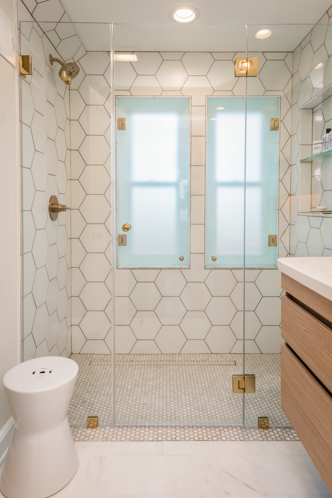 Walk-in shower - small contemporary master white tile and ceramic tile marble floor and white floor walk-in shower idea in Milwaukee with flat-panel cabinets, light wood cabinets, a wall-mount toilet, white walls, an integrated sink, solid surface countertops, a hinged shower door and white countertops