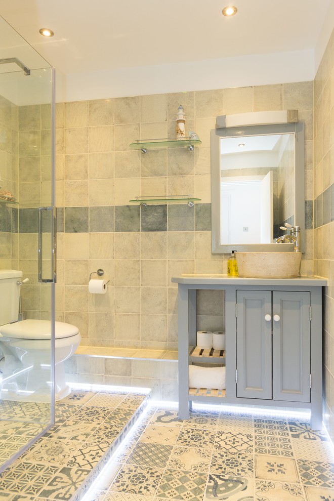 Mid-sized minimalist kids' yellow tile and stone tile ceramic tile and multicolored floor doorless shower photo in London with raised-panel cabinets, gray cabinets, a two-piece toilet, yellow walls, a vessel sink, soapstone countertops and a hinged shower door