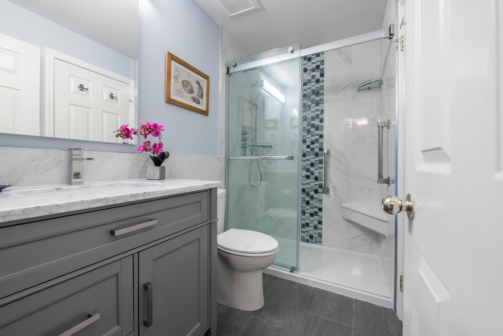 На фото: ванная комната среднего размера в современном стиле с фасадами с утопленной филенкой, серыми фасадами, душем в нише, раздельным унитазом, белой плиткой, мраморной плиткой, синими стенами, полом из керамогранита, душевой кабиной, врезной раковиной, мраморной столешницей, серым полом, душем с раздвижными дверями и белой столешницей