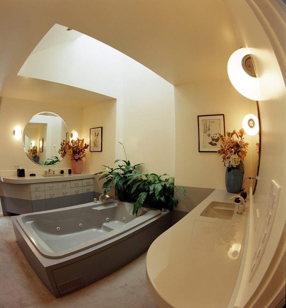 Aménagement d'une grande salle de bain principale contemporaine avec un lavabo encastré, des portes de placard grises, un plan de toilette en granite, une baignoire indépendante et un mur beige.