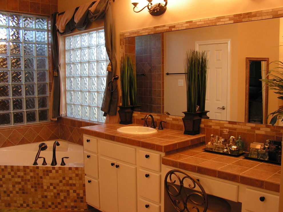 Стильный дизайн: большая главная ванная комната в средиземноморском стиле с плоскими фасадами, белыми фасадами, угловой ванной, бежевой плиткой, оранжевой плиткой, каменной плиткой, бежевыми стенами и накладной раковиной - последний тренд