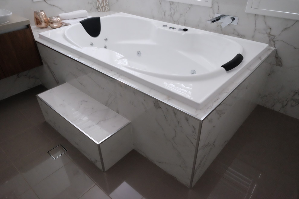 Inspiration för mellanstora moderna beige en-suite badrum, med luckor med infälld panel, skåp i mellenmörkt trä, ett platsbyggt badkar, en kantlös dusch, en vägghängd toalettstol, vit kakel, marmorkakel, vita väggar, ett fristående handfat, bänkskiva i kvarts, grått golv, med dusch som är öppen och klinkergolv i porslin