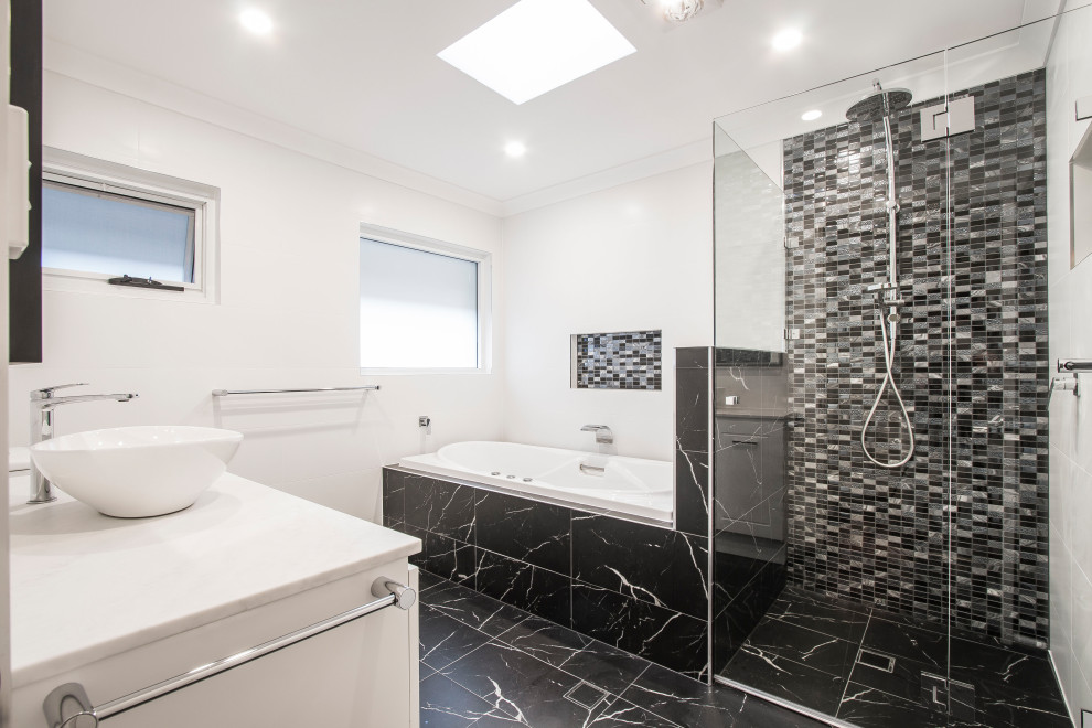 Стильный дизайн: большая главная ванная комната в стиле модернизм с фасадами с утопленной филенкой, белыми фасадами, гидромассажной ванной, угловым душем, унитазом-моноблоком, белой плиткой, керамической плиткой, белыми стенами, полом из цементной плитки, настольной раковиной, столешницей из искусственного кварца, черным полом, душем с распашными дверями, желтой столешницей, нишей, тумбой под одну раковину, встроенной тумбой и кессонным потолком - последний тренд