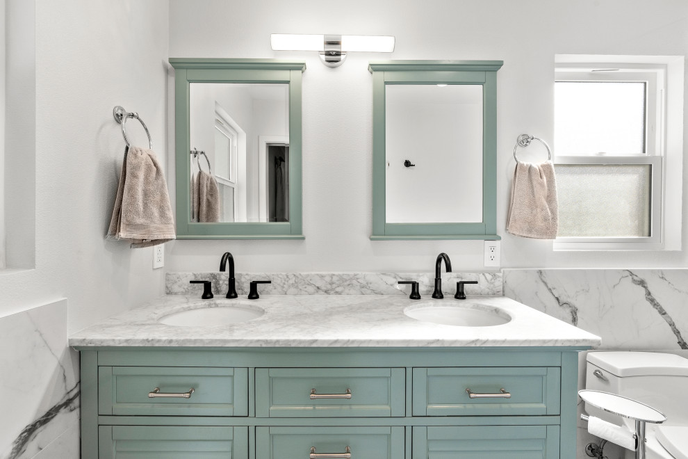 Foto på ett stort badrum, med turkosa skåp, svart och vit kakel, porslinskakel, klinkergolv i porslin, marmorbänkskiva och flerfärgat golv