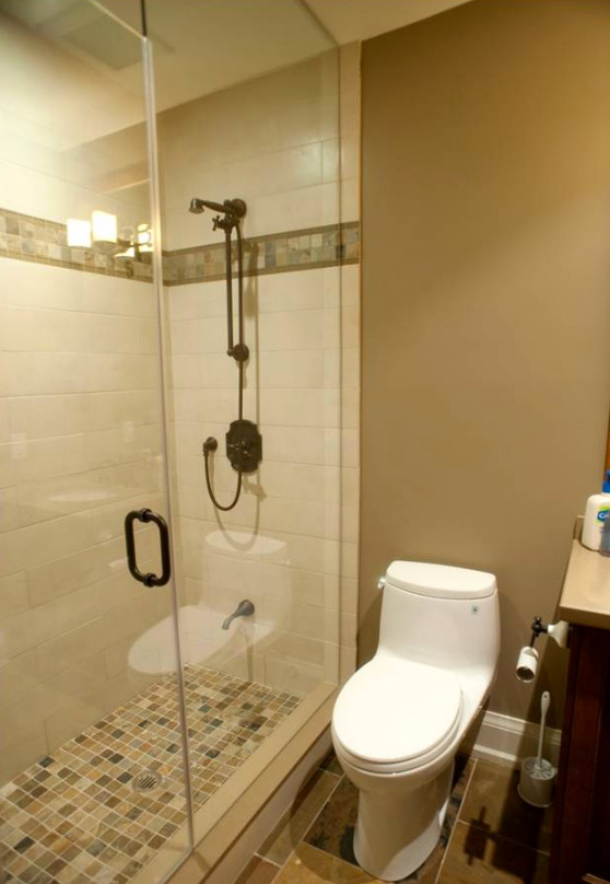 Cette image montre une petite salle d'eau craftsman en bois foncé avec un placard à porte shaker, une douche d'angle, WC à poser, un mur beige, un sol en ardoise, un lavabo encastré et un plan de toilette en surface solide.
