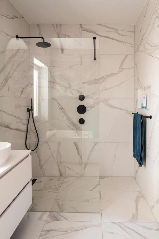 Exempel på ett mellanstort modernt vit vitt en-suite badrum, med släta luckor, vita skåp, en kantlös dusch, vit kakel, marmorkakel, vita väggar, klinkergolv i keramik, ett konsol handfat, bänkskiva i kvarts, vitt golv och med dusch som är öppen