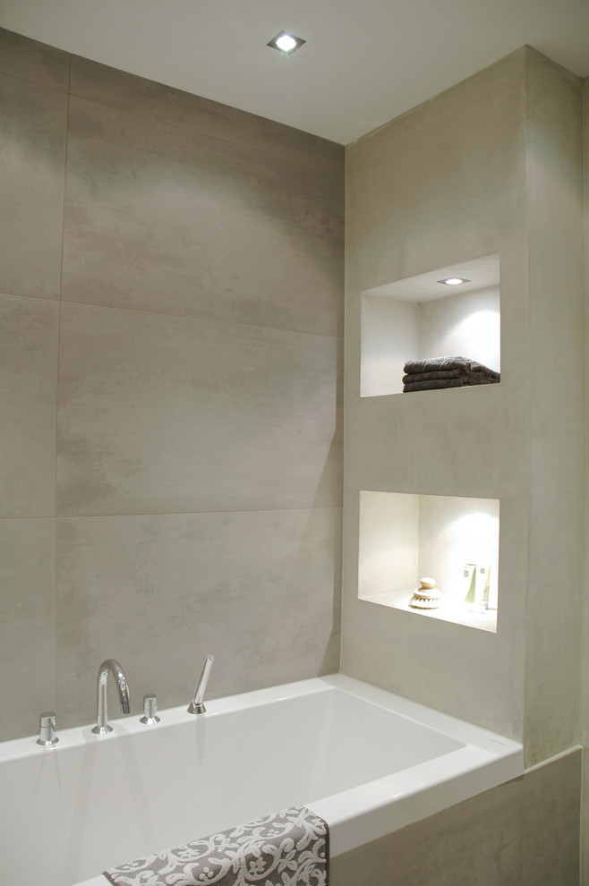 Idee per una stanza da bagno moderna con vasca da incasso e piastrelle grigie