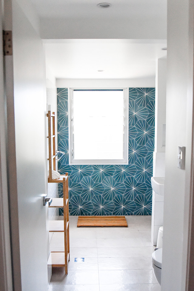 Alcove shower - mid-sized coastal master blue tile and ceramic tile ceramic tile and gray floor alcove shower idea in Gold Coast - Tweed with open cabinets, light wood cabinets, a one-piece toilet, white walls and a wall-mount sink