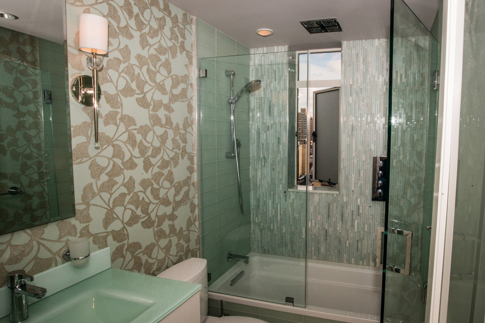 На фото: маленькая ванная комната в современном стиле с душевой кабиной, белыми фасадами, ванной в нише, душем над ванной, раздельным унитазом, синей плиткой, зеленой плиткой, стеклянной плиткой, разноцветными стенами, монолитной раковиной и стеклянной столешницей для на участке и в саду