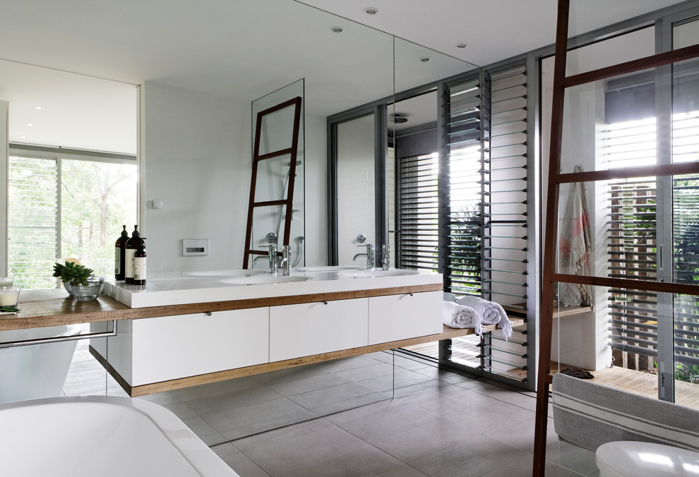 Idéer för ett mellanstort modernt vit en-suite badrum, med luckor med profilerade fronter, skåp i mellenmörkt trä, ett fristående badkar, en öppen dusch, en vägghängd toalettstol, spegel istället för kakel, klinkergolv i porslin, ett integrerad handfat, träbänkskiva, grått golv och med dusch som är öppen