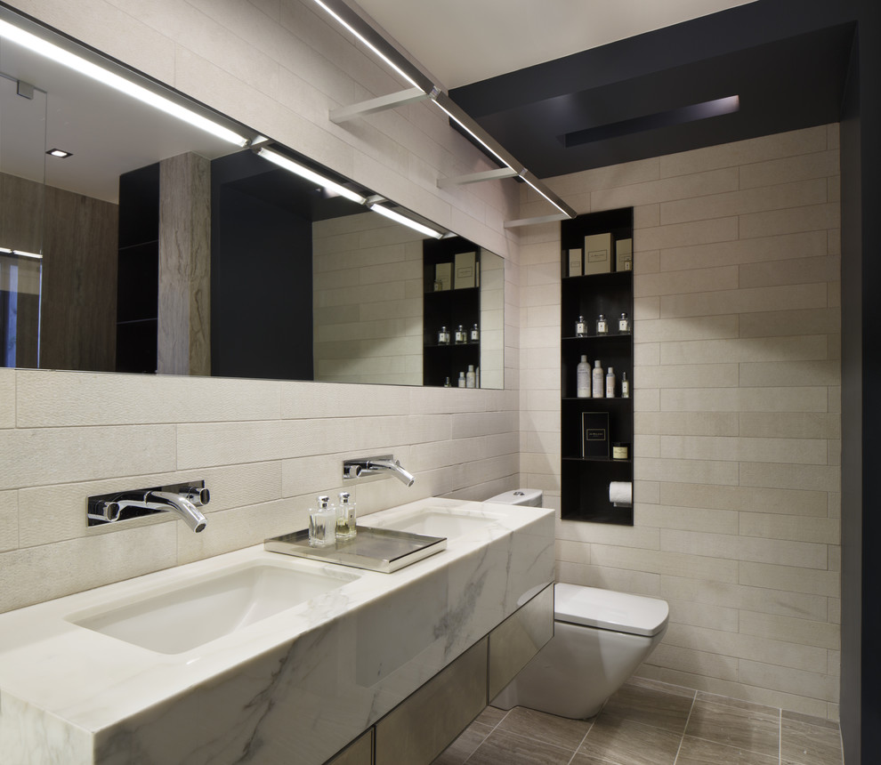 Esempio di una stanza da bagno moderna con lavabo sospeso, top in marmo, WC monopezzo, piastrelle beige e piastrelle in ceramica