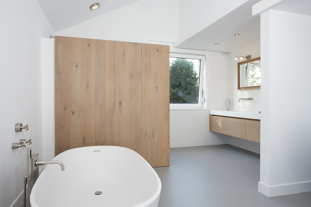 Идея дизайна: ванная комната в современном стиле с плоскими фасадами, светлыми деревянными фасадами, отдельно стоящей ванной и окном