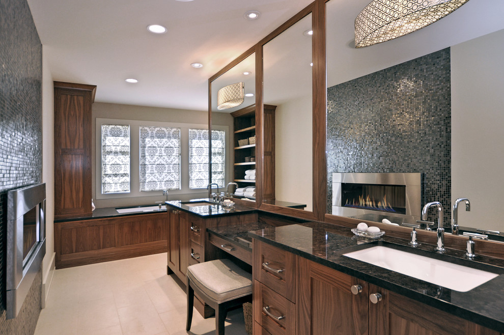 Foto di una stanza da bagno chic con piastrelle a mosaico, ante in stile shaker, ante in legno bruno, vasca sottopiano, piastrelle grigie, pareti beige, lavabo sottopiano e top in granito