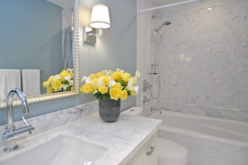 Modelo de cuarto de baño clásico renovado con bañera encastrada, combinación de ducha y bañera, baldosas y/o azulejos blancos, baldosas y/o azulejos de piedra, paredes azules, lavabo bajoencimera y encimera de mármol