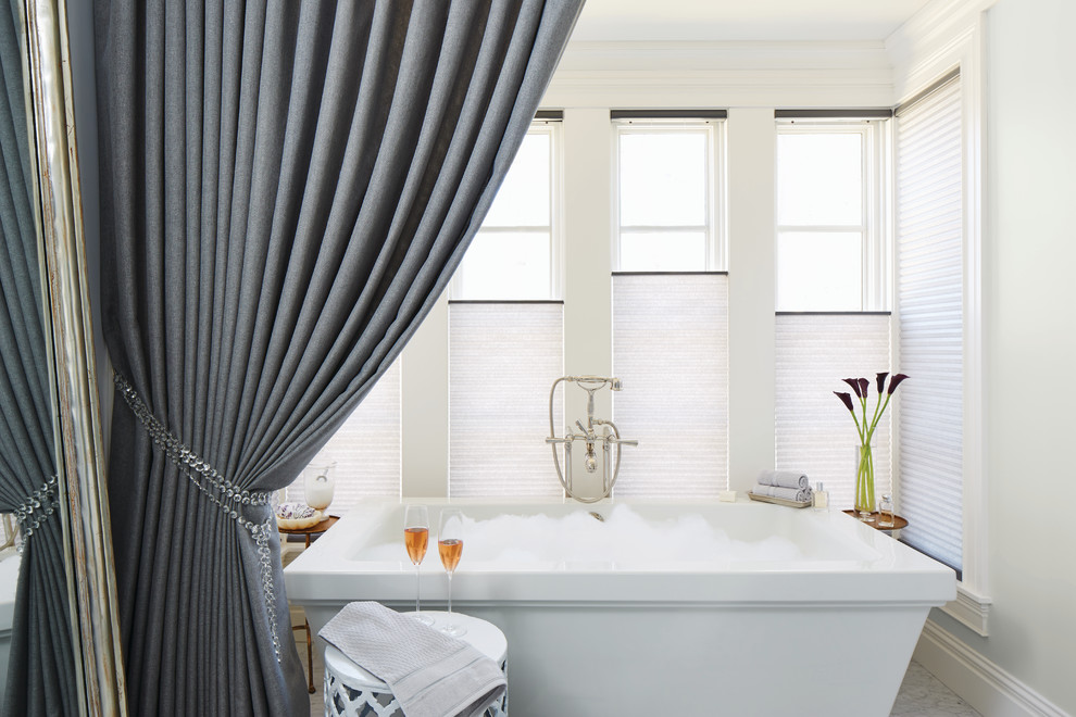 На фото: большая главная ванная комната в средиземноморском стиле с отдельно стоящей ванной, белыми стенами и мраморным полом с
