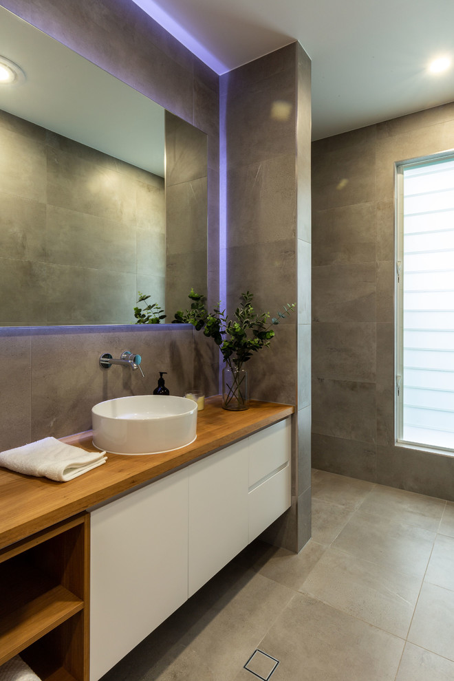 Идея дизайна: ванная комната среднего размера в стиле модернизм с светлыми деревянными фасадами, открытым душем, серой плиткой, серыми стенами, столешницей из дерева, серым полом и открытым душем