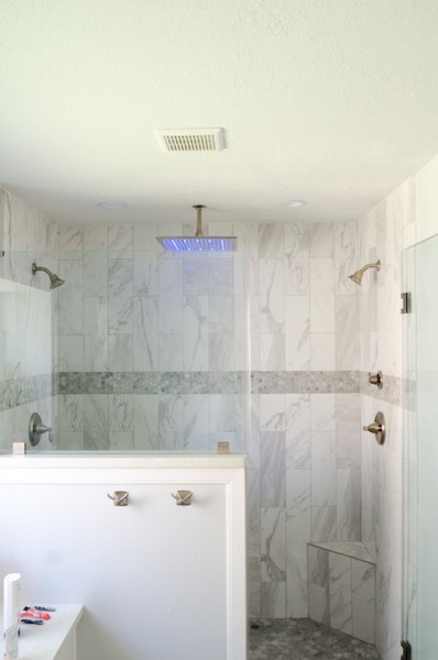 Exemple d'une salle de bain bord de mer avec un placard à porte shaker, des portes de placard blanches, un carrelage multicolore, un mur blanc, un lavabo encastré, un sol beige et une cabine de douche à porte battante.