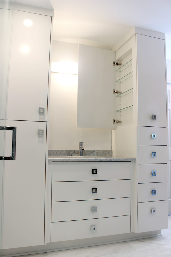 Cette image montre une salle de bain principale minimaliste de taille moyenne avec des portes de placard blanches, un lavabo encastré, un placard à porte plane, un plan de toilette en marbre, une douche ouverte, WC à poser, un carrelage blanc, un mur gris et un sol en marbre.
