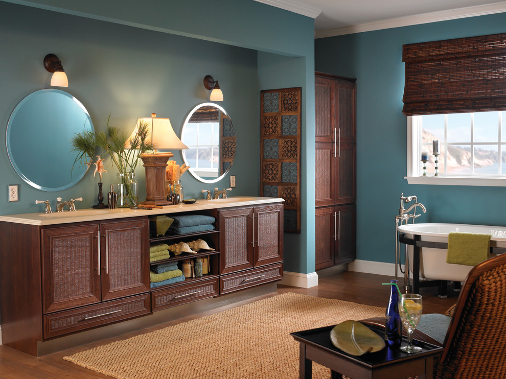 Foto di una stanza da bagno padronale tropicale con lavabo da incasso, ante a persiana, ante in legno scuro, vasca freestanding, pareti blu e pavimento in legno massello medio