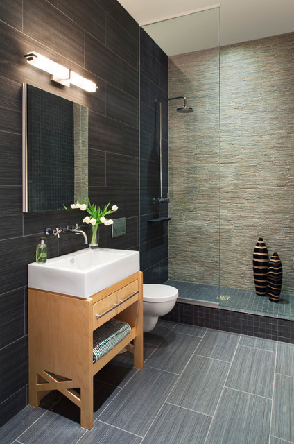 Mid-sized trendy master gray tile and porcelain tile porcelain tile and gray floor doorless shower photo in Indianapolis with furniture-like cabinets, light wood cabinets, a wall-mount toilet, gray walls, a console sink and a hinged shower door