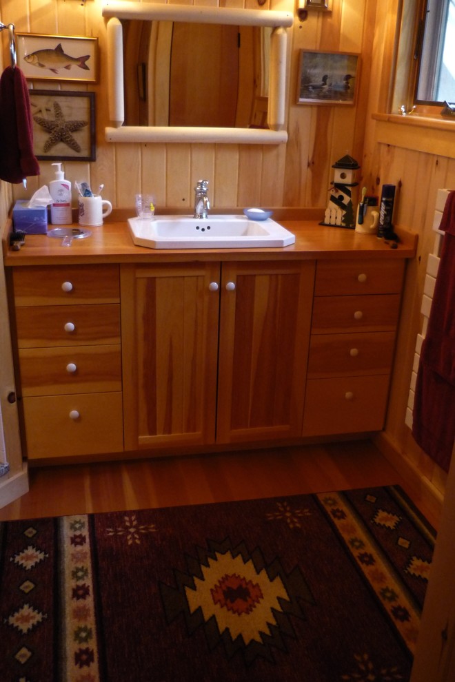Modelo de cuarto de baño principal rústico con armarios con paneles lisos, puertas de armario de madera clara y encimera de madera