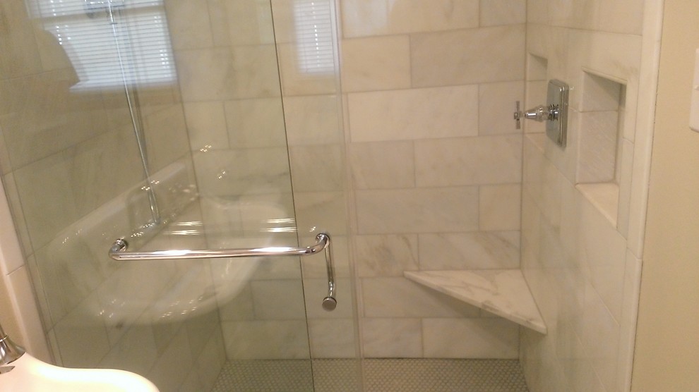 Klassisk inredning av ett litet en-suite badrum, med ett avlångt handfat, en kantlös dusch, en toalettstol med hel cisternkåpa, vit kakel, stenkakel, beige väggar och mosaikgolv