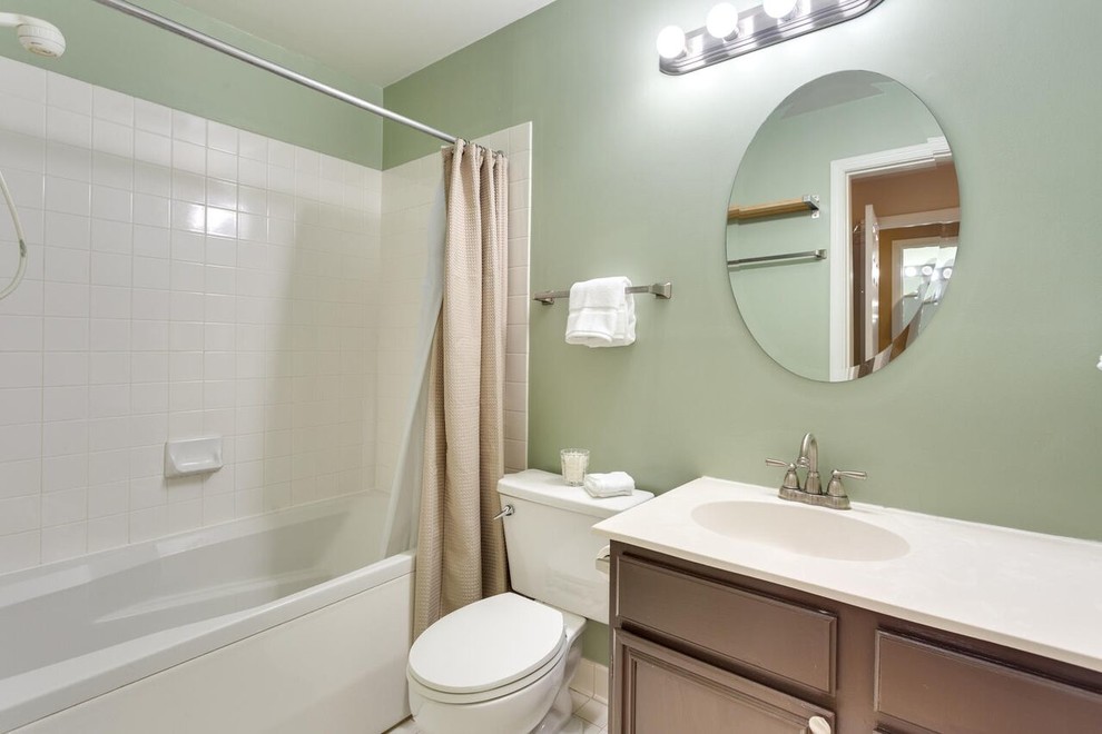 Medium sized classic ensuite bathroom in Baltimore with an integrated sink, raised-panel cabinets, medium wood cabinets, a corner bath, a shower/bath combination, a one-piece toilet and green walls.